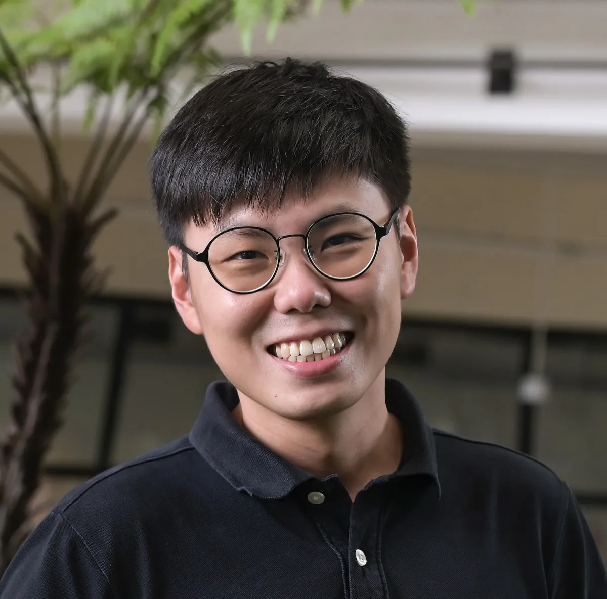 Marcus Wong, smiling, wearing glasses and a dark polo shirt